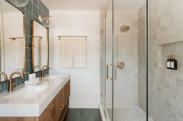 a bathroom with a double vanity sink mirror and shower