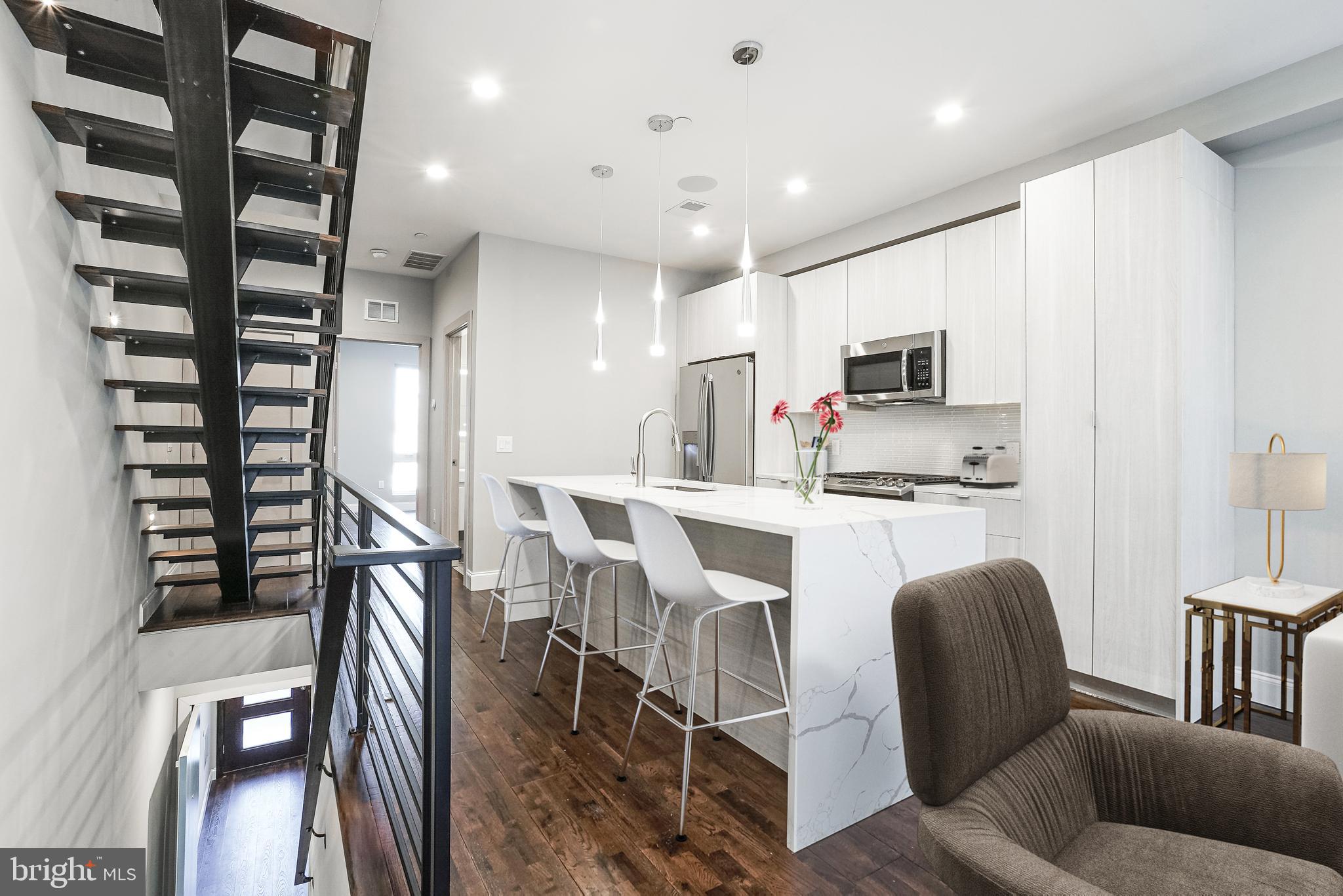 1630 Cambridge Street, Unit B Philadelphia, PA 19130 - Photo 3 of 24 a kitchen with stainless steel appliances kitchen island granite countertop a refrigerator a stove a microwave oven a dining table and chairs with wooden floor