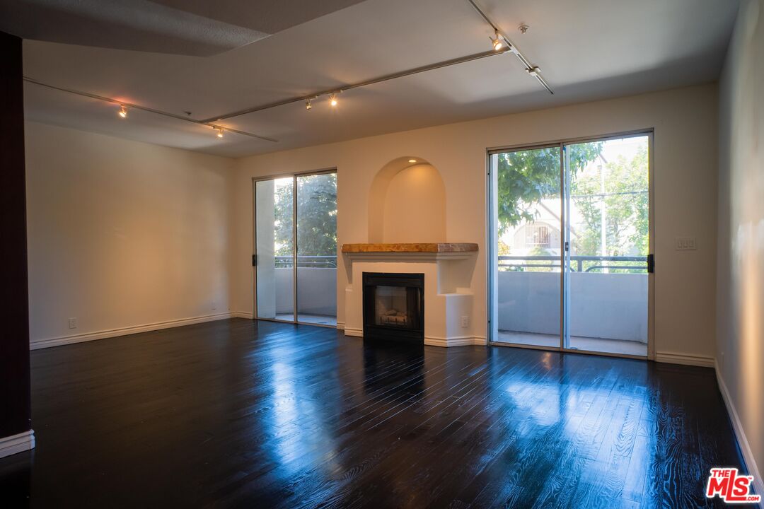 an empty room with wooden floor fireplace and windows