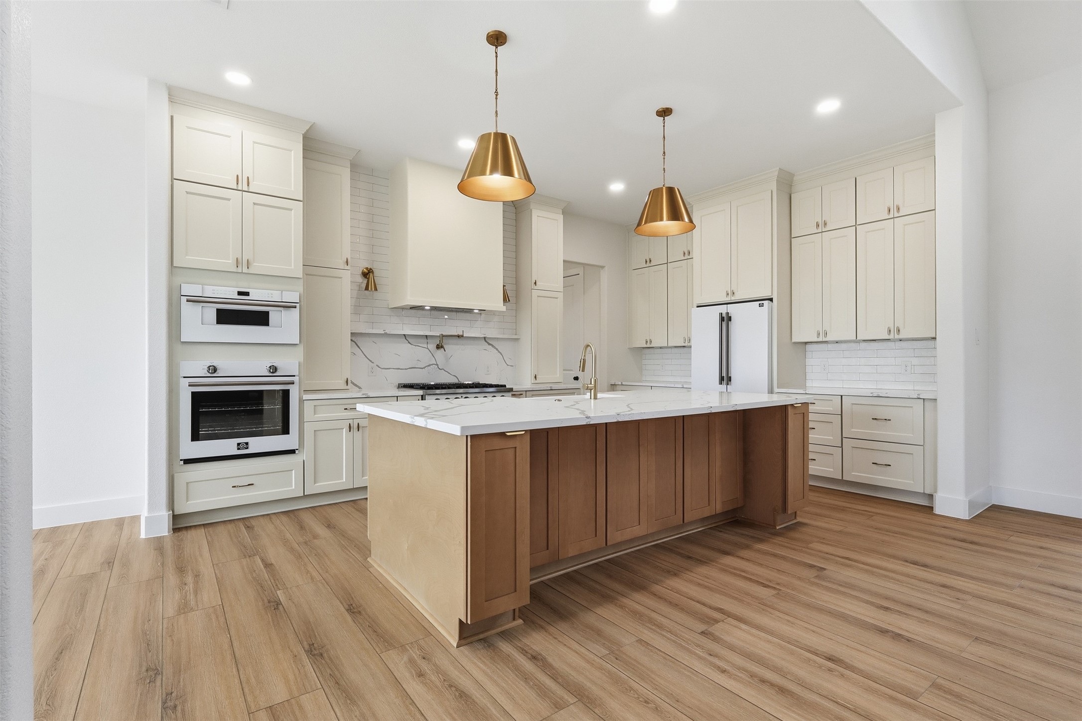 a large kitchen with stainless steel appliances kitchen island granite countertop a stove a sink and white cabinets with wooden floor
