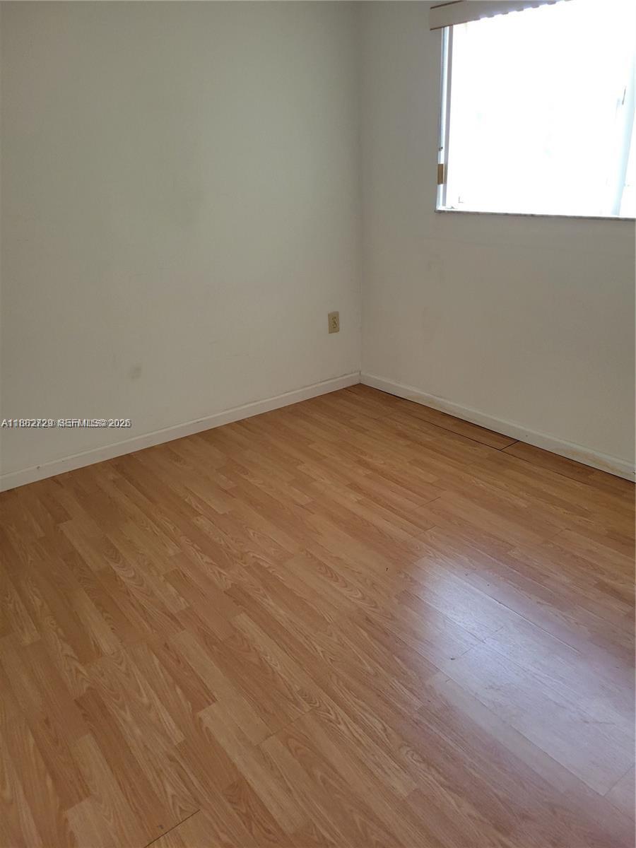 2680 West 76th Street, Unit 204 Hialeah, FL 33016 - Photo 5 of 14 an empty room with wooden floor and windows