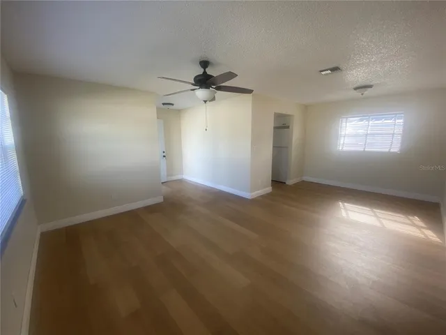 an empty room with wooden floor cabinet and windows