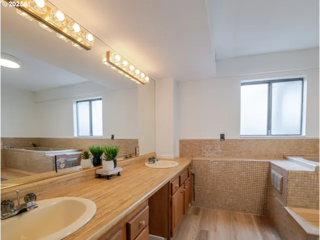 a bathroom with a granite countertop sink a large mirror and a bathtub