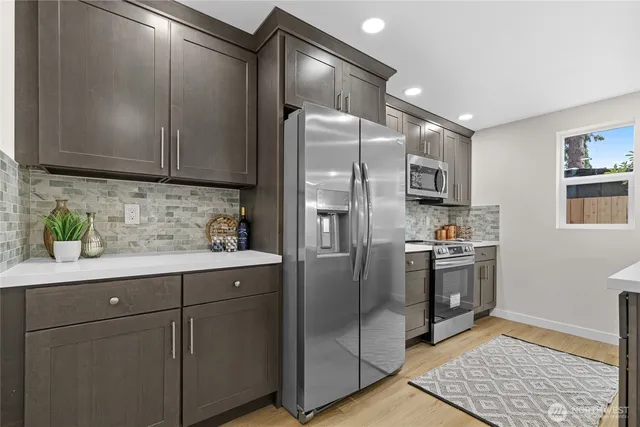 a kitchen with stainless steel appliances granite countertop a refrigerator a sink a stove a microwave a sink and dishwasher