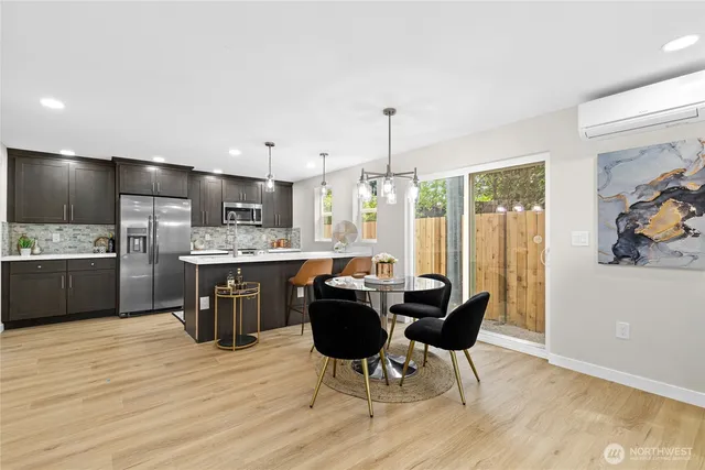 a kitchen with kitchen island stainless steel appliances a dining table chairs and sink