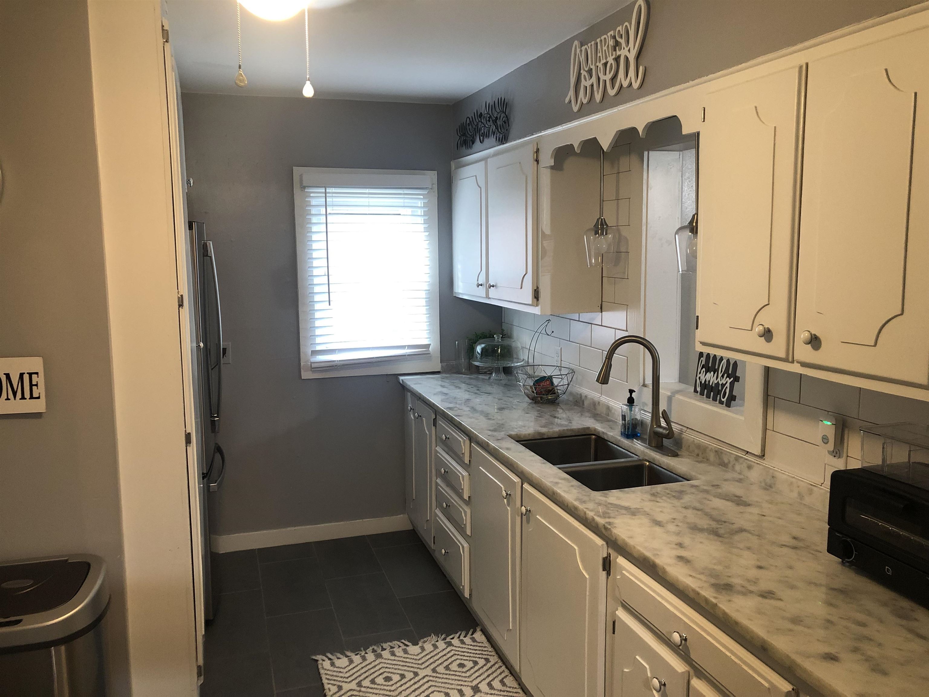 1563 Railton Road Memphis, TN 38111 - Photo 4 of 17 Kitchen with white cabinetry, decorative backsplash, dark tile patterned flooring, and freestanding refrigerator