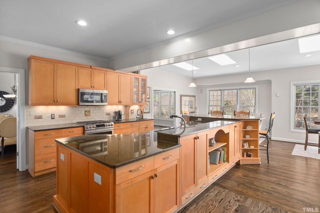 a kitchen with stainless steel appliances granite countertop a stove top oven a sink dishwasher and a refrigerator with wooden floor