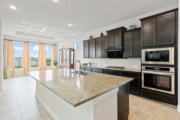 a kitchen with stainless steel appliances granite countertop a refrigerator a stove and a sink with wooden floor