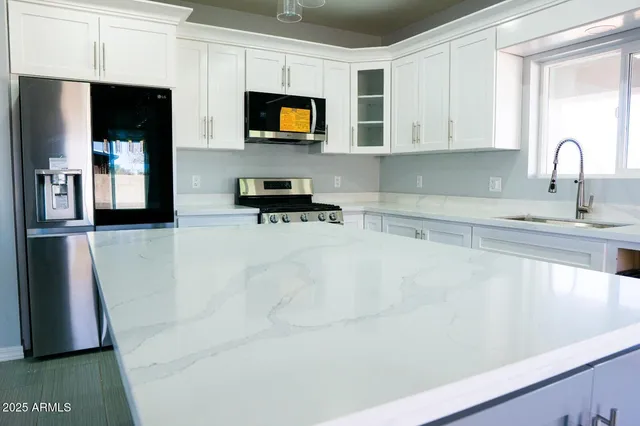 a kitchen with kitchen island white cabinets and stainless steel appliances