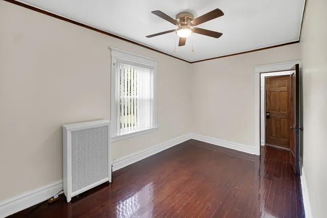 an empty room with wooden floor ceiling fan and windows