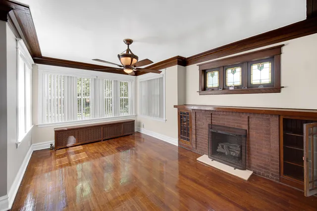 a view of an empty room with wooden floor fireplace and a window
