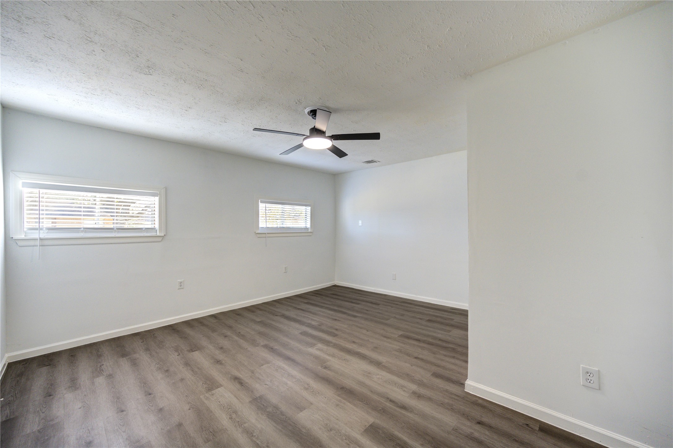 12127 Palmton Street Houston, TX 77034 - Photo 13 of 31 an empty room with wooden floor ceiling fan and windows