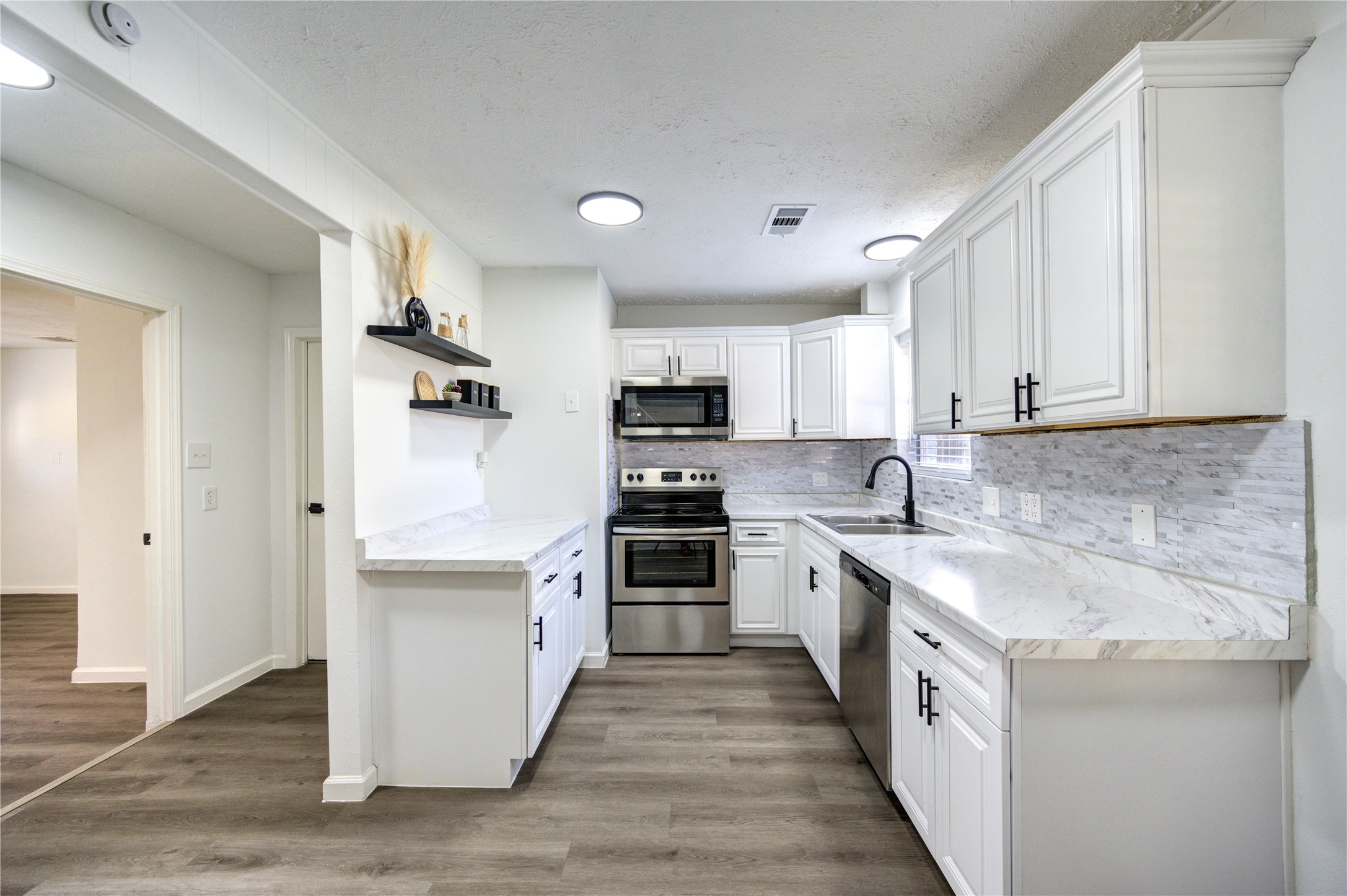 12127 Palmton Street Houston, TX 77034 - Photo 5 of 31 a kitchen with stainless steel appliances granite countertop a stove top oven a sink and white cabinets