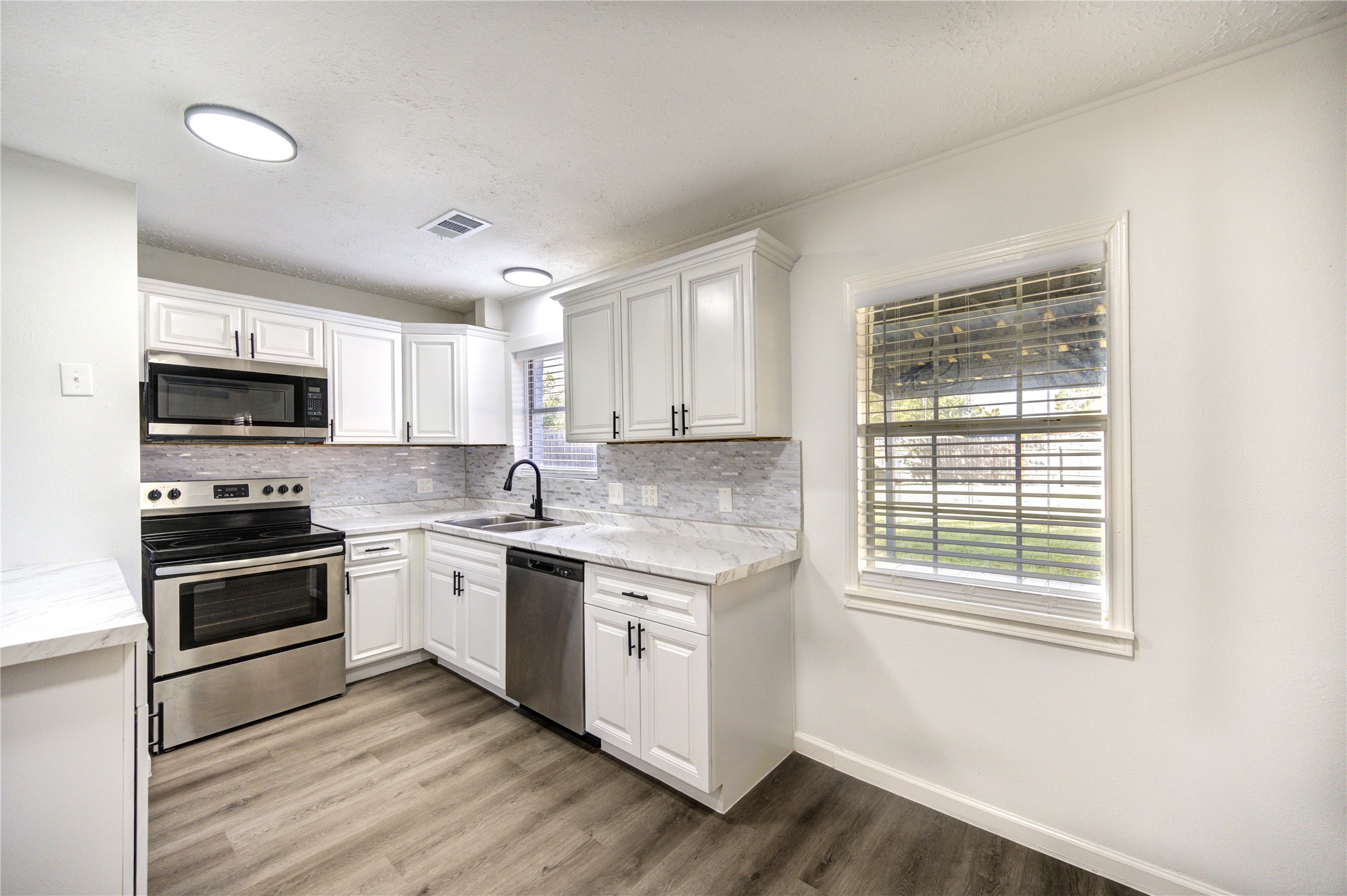 12127 Palmton Street Houston, TX 77034 - Photo 9 of 31 a kitchen with stainless steel appliances granite countertop a stove a sink and a microwave