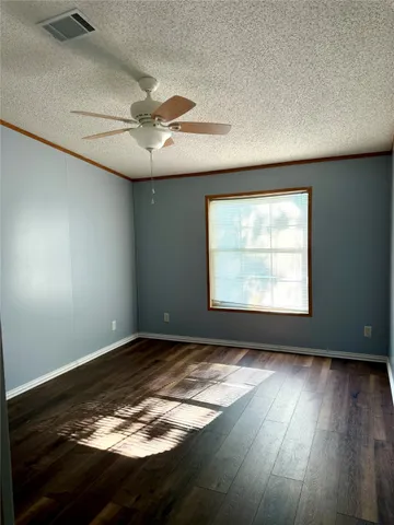 an empty room with wooden floor fan and windows