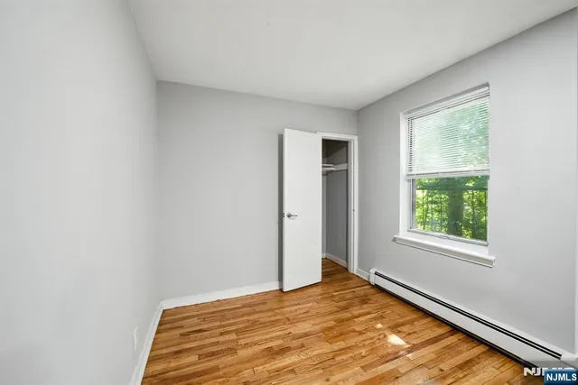 a view of a bedroom with wooden floor and a window