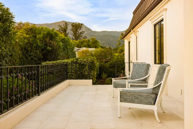 a view of two chairs and a table in the balcony
