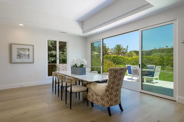 a dining room with furniture large windows and wooden floor
