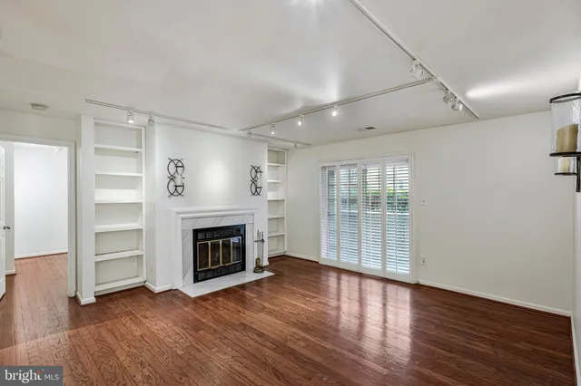an empty room with wooden floor fireplace and windows