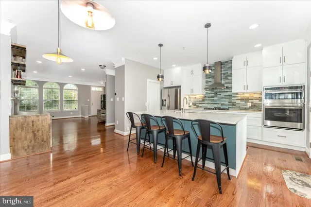 a open kitchen with stainless steel appliances granite countertop a stove top oven a refrigerator a dining table and chairs with wooden floor