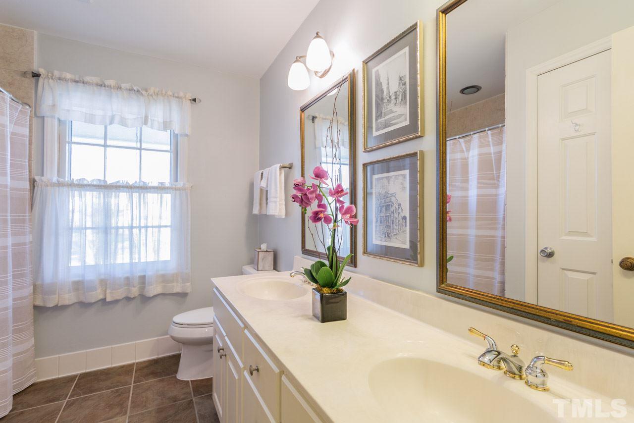 7616 Harps Mill Road Raleigh, NC 27615 - Photo 19 of 24 Tub/shower combination with tile surround and a vanity with double sinks.