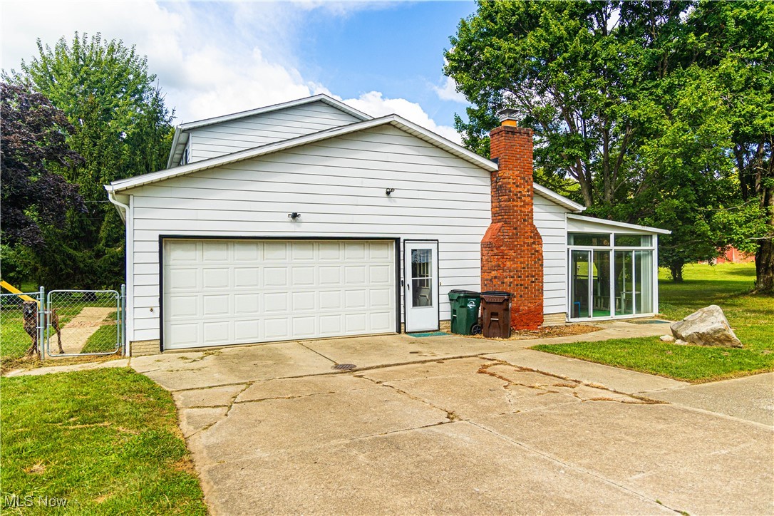 16974 Hawley Road Oberlin, OH 44074 - Photo 32 of 42 View of home's exterior with driveway, a sunroom, a gate, a chimney, and an attached garage