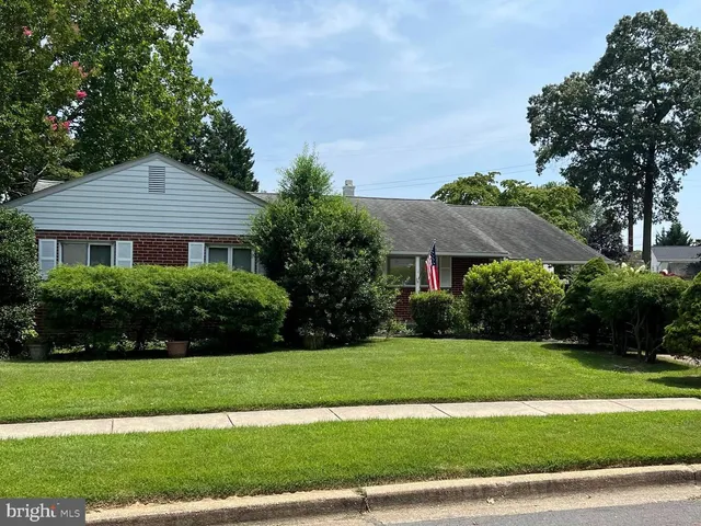 a view of a white house next to a yard with big trees