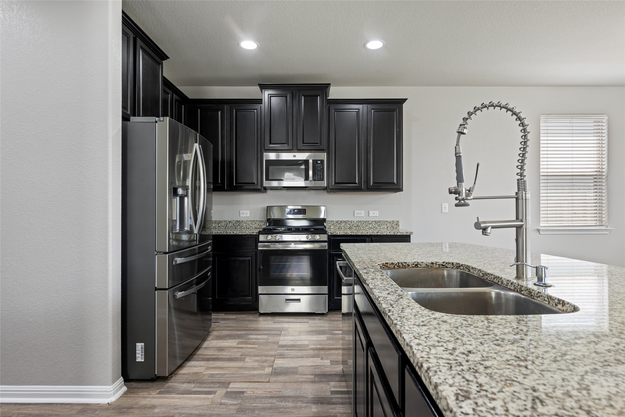 124 Guemal Road Buda, TX 78610 - Photo 16 of 40 Modern kitchen with granite countertops, stainless steel appliances, and dark wood cabinetry.