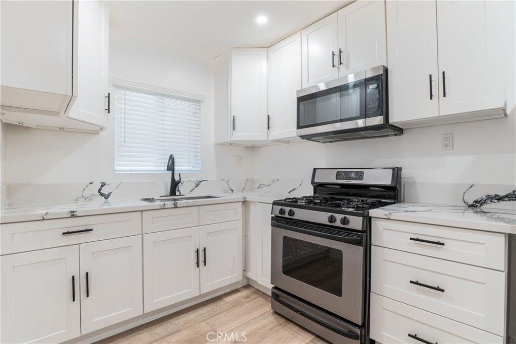 7348 Florence Avenue, Unit 4 Downey, CA 90240 - Photo 3 of 16 a kitchen with white cabinets and stainless steel appliances