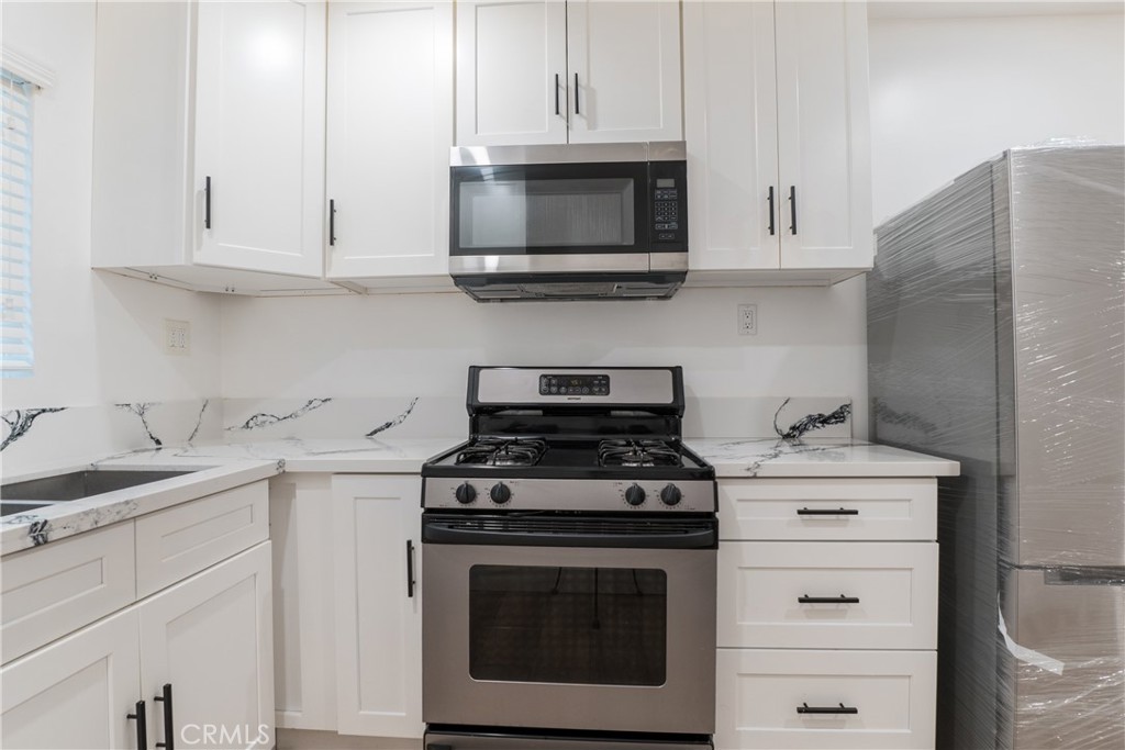 7348 Florence Avenue, Unit 4 Downey, CA 90240 - Photo 4 of 16 a kitchen with stainless steel appliances granite countertop a stove a microwave and a white cabinets
