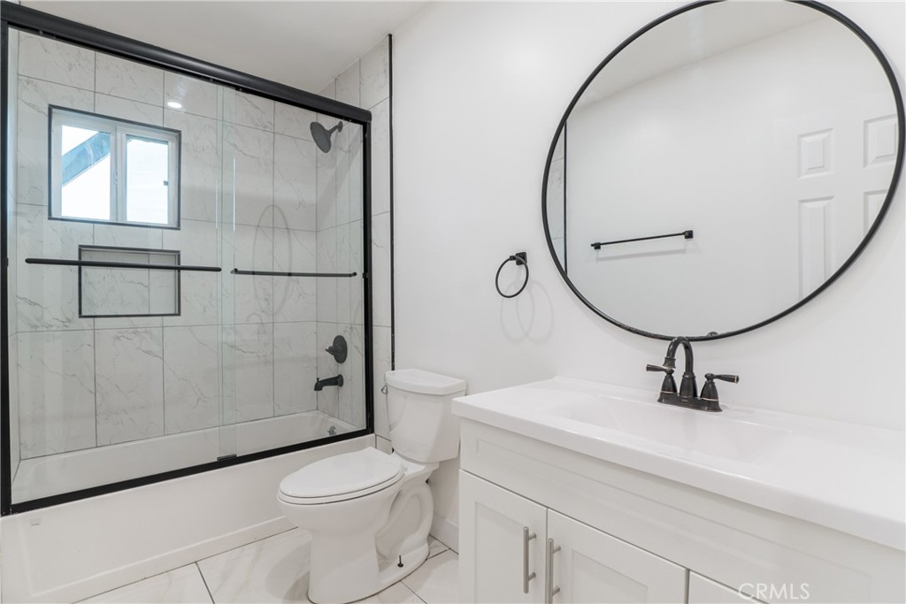 7348 Florence Avenue, Unit 4 Downey, CA 90240 - Photo 5 of 16 a bathroom with a sink a mirror a toilet and shower