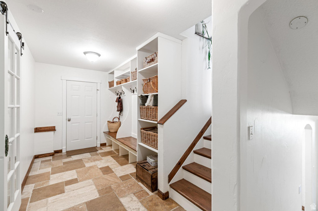 814 Mountain Road Logan, UT 84321 - Photo 21 of 42 Entryway featuring natural stone tile flooring, a built-in bench with integrated shelving, dark wood stair treads, white painted risers, and a dark wood handrail