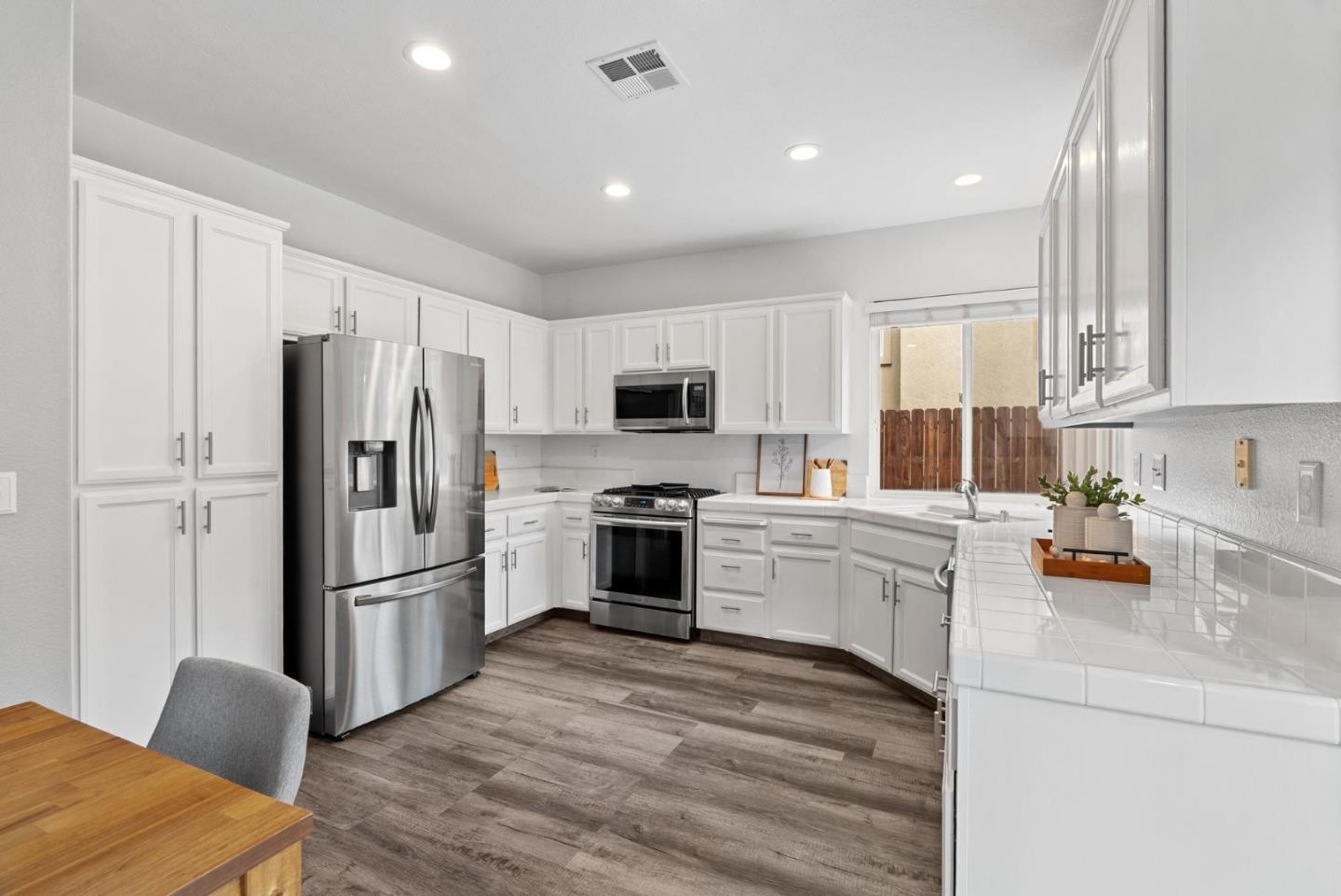 56 Lavender Court Tracy, CA 95376 - Photo 11 of 56 a kitchen with refrigerator a microwave a stove and white cabinets with wooden floor