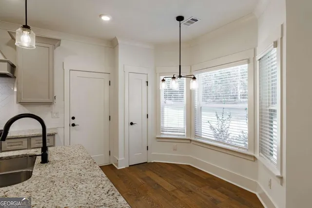 a view of an empty room with a window and kitchen view
