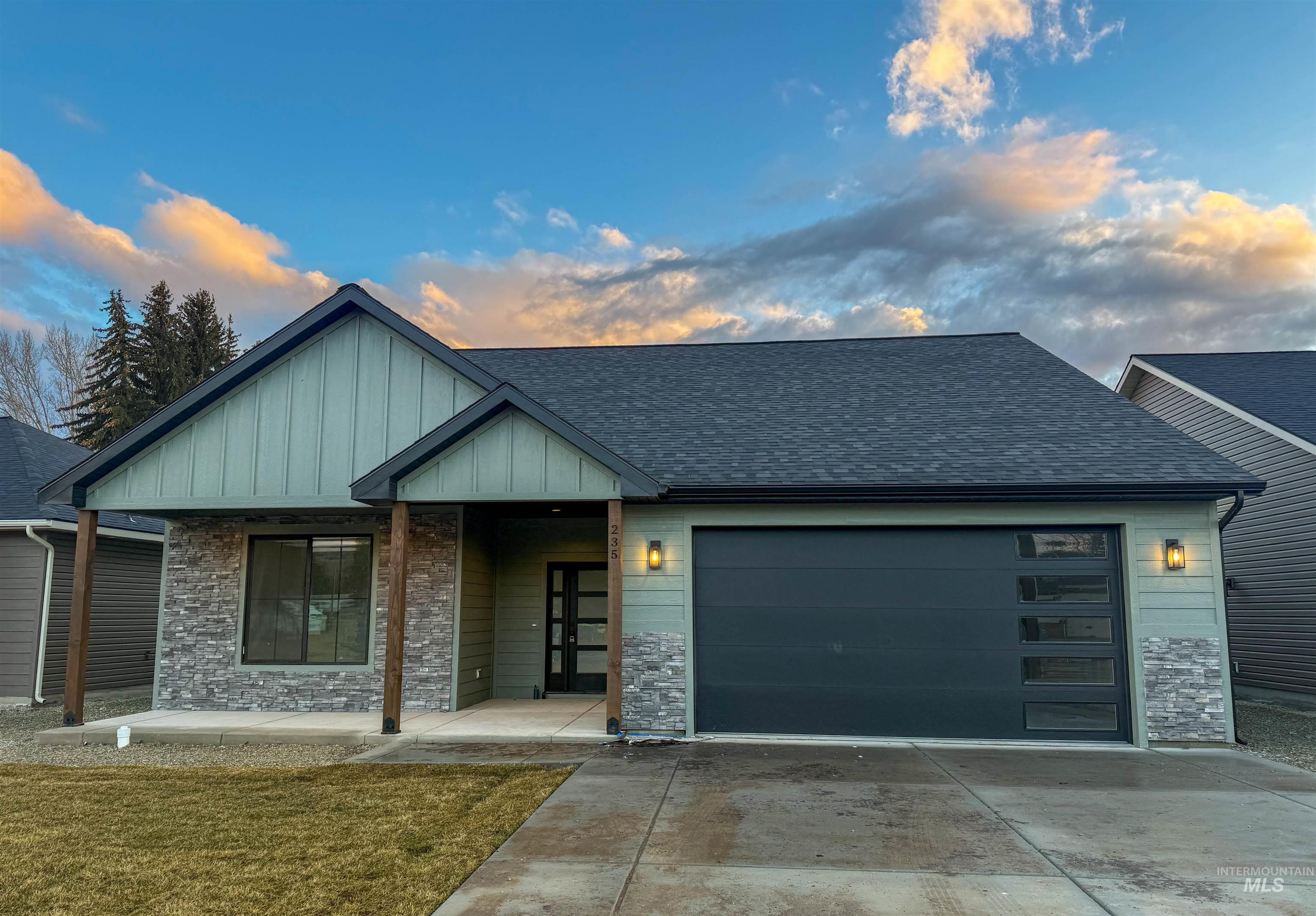 View of front of property featuring stone siding and roof with shingles
