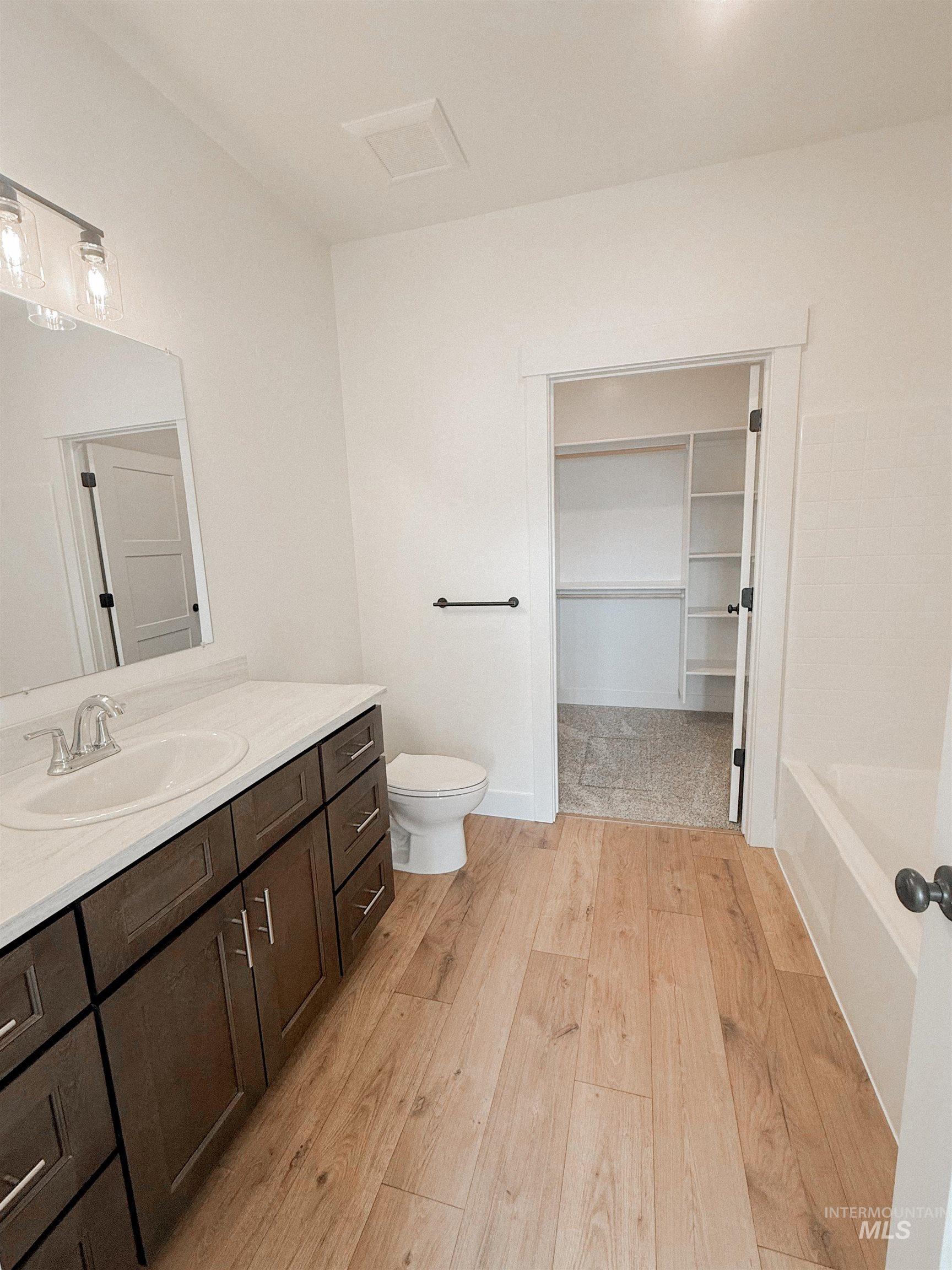 235 Whitman Street Albion, ID 83311 - Photo 13 of 23 Bathroom with vanity, a spacious closet, light wood-style floors, and a tub