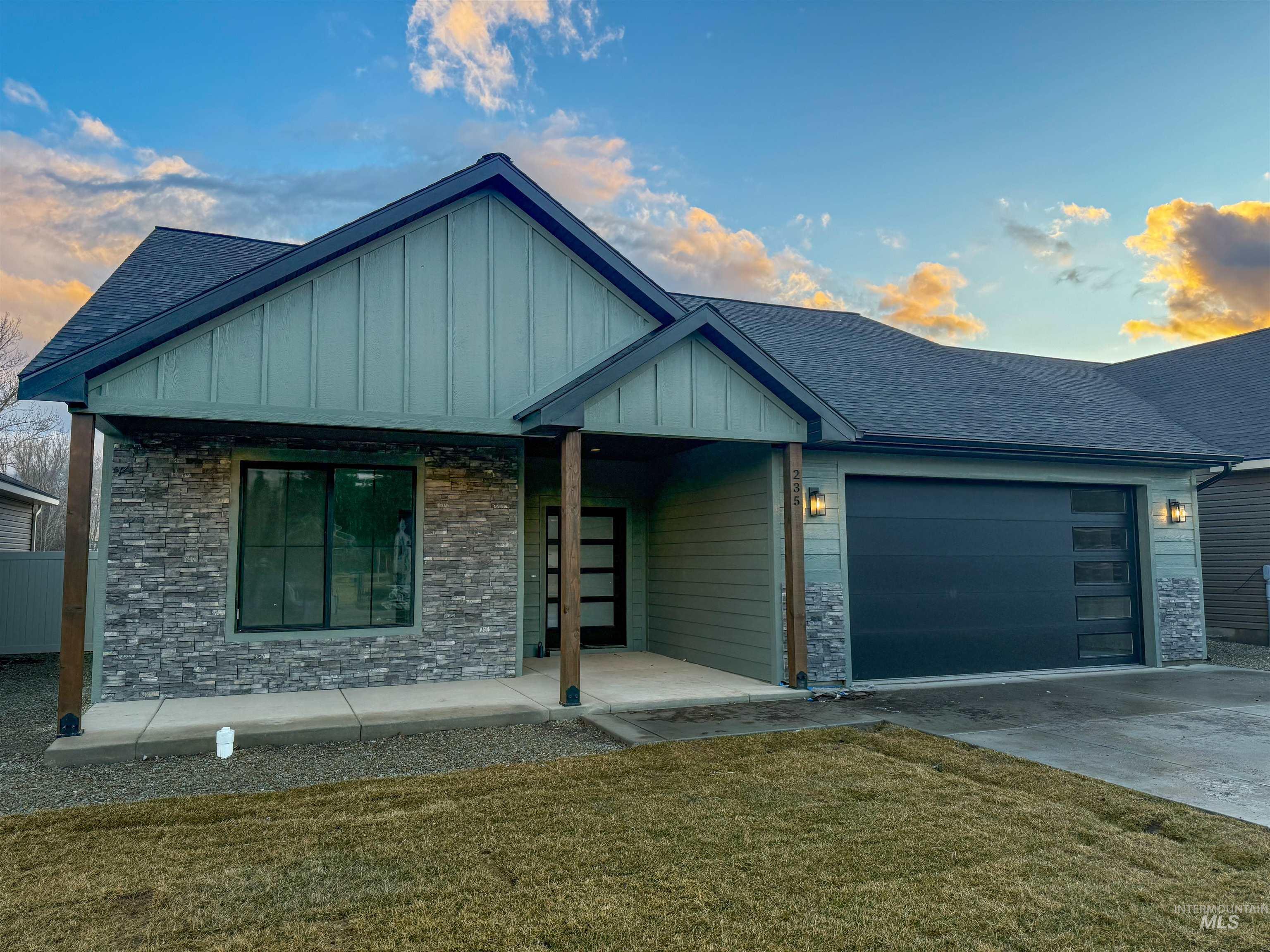 235 Whitman Street Albion, ID 83311 - Photo 2 of 23 View of front of home with roof with shingles, a front yard, an attached garage, board and batten siding, and driveway