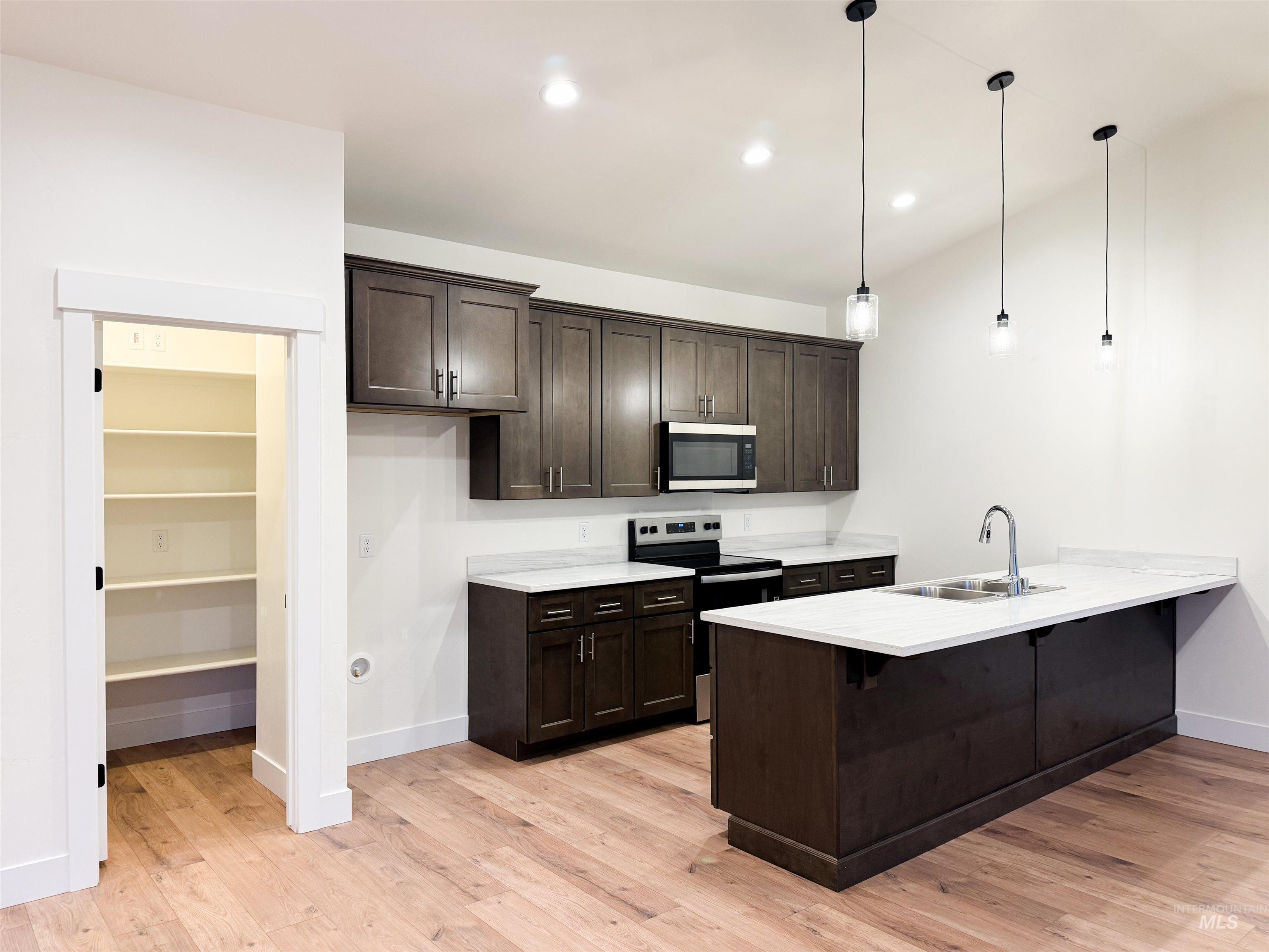235 Whitman Street Albion, ID 83311 - Photo 5 of 23 Kitchen with a kitchen bar, dark brown cabinetry, appliances with stainless steel finishes, pendant lighting, and a peninsula