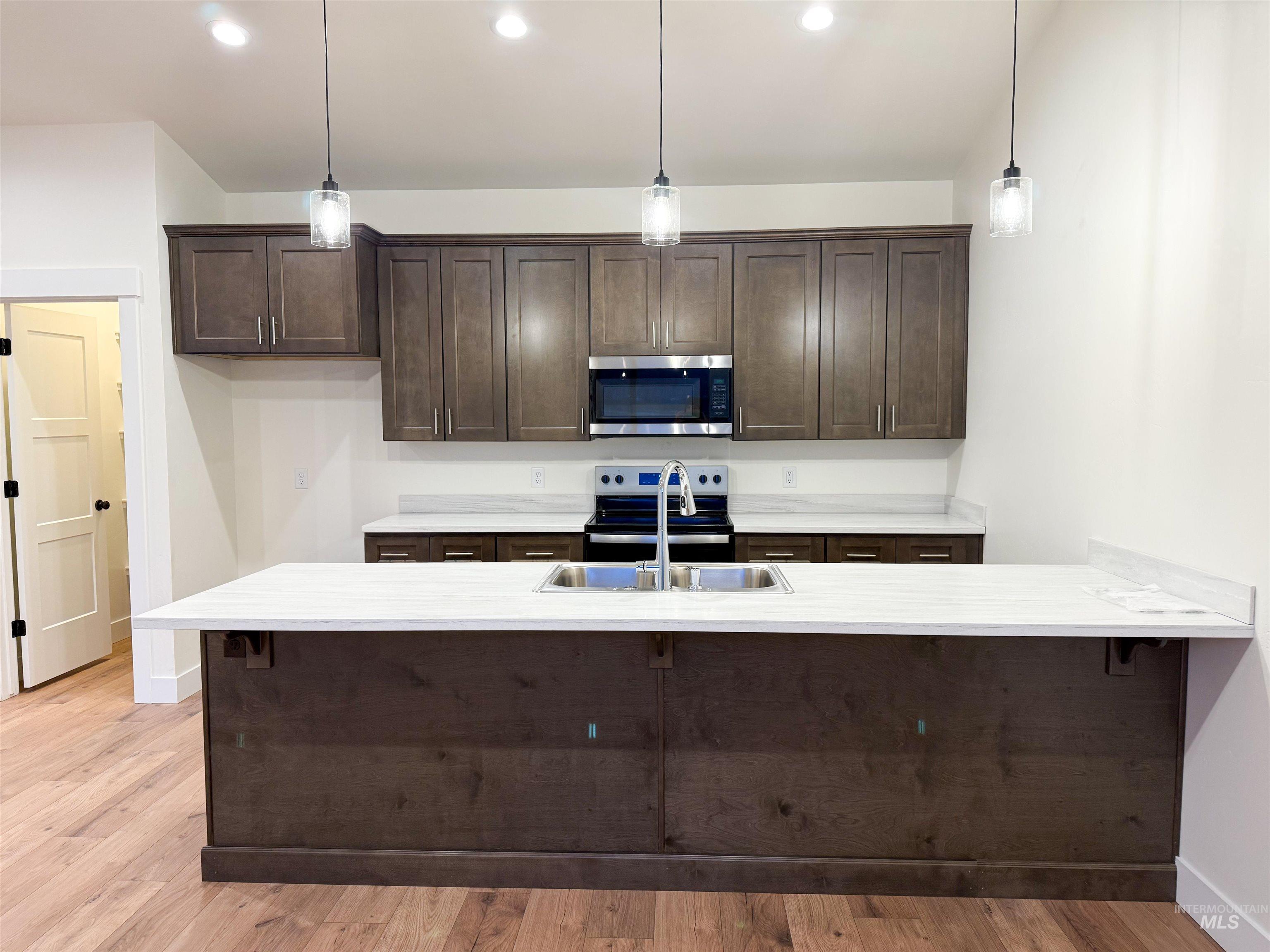 235 Whitman Street Albion, ID 83311 - Photo 10 of 23 Kitchen featuring dark brown cabinetry, a peninsula, stainless steel appliances, pendant lighting, and a kitchen breakfast bar