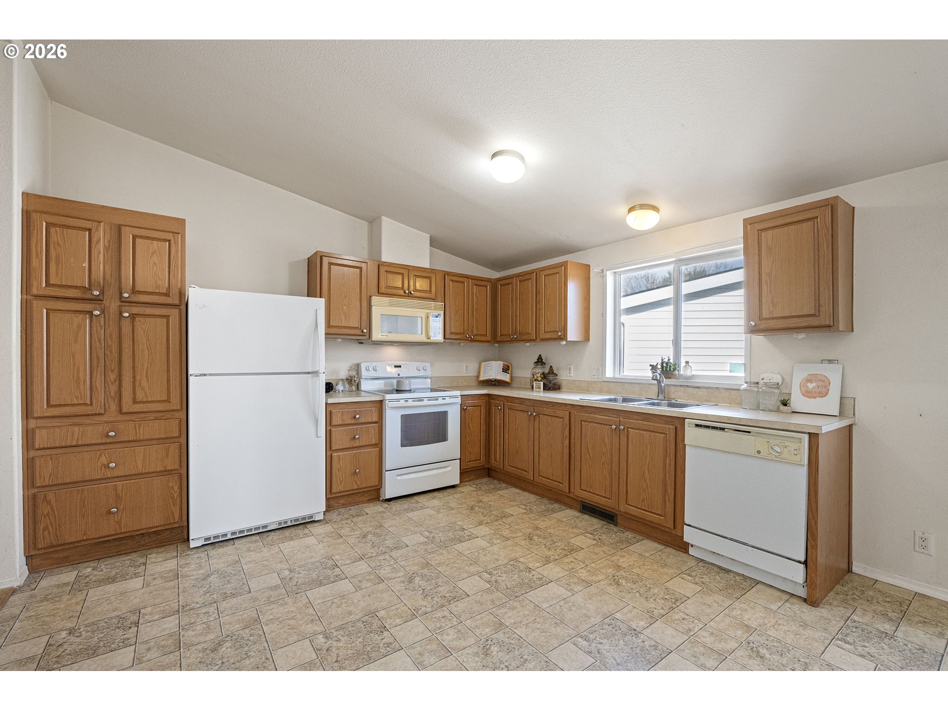 1699 North Terry Street, Unit 320 Eugene, OR 97402 - Photo 14 of 36 a kitchen with a refrigerator and white cabinets