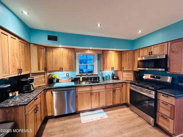 a kitchen with stainless steel appliances granite countertop a stove a sink and a microwave