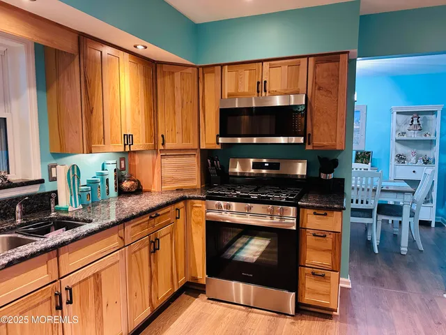 a kitchen with stainless steel appliances granite countertop a stove top oven a sink and a microwave