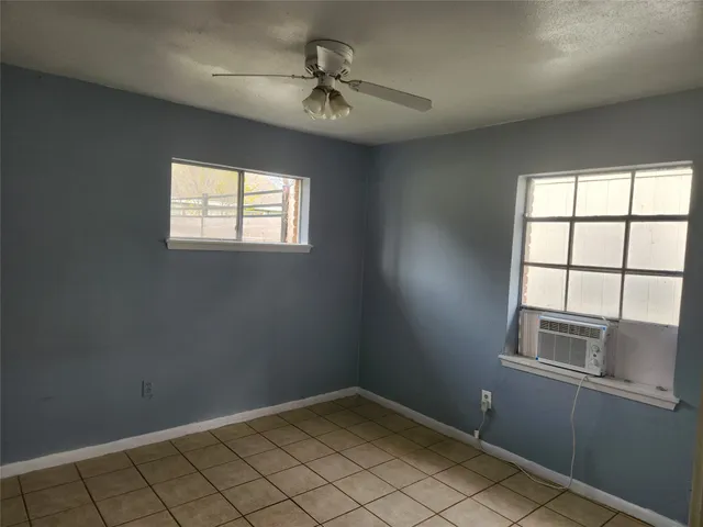 an empty room with windows and fan