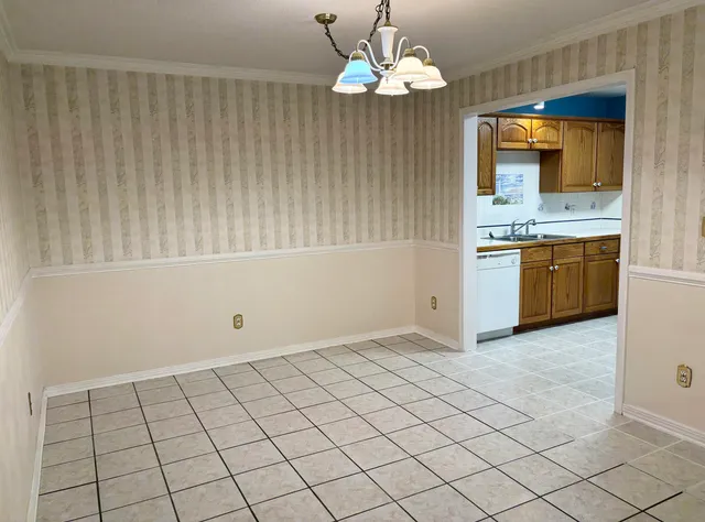 an empty room with kitchen and chandelier
