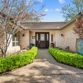a view of a house with brick walls plants and large tree