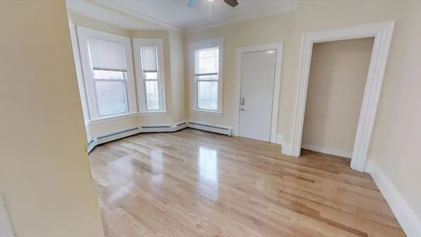 an empty room with wooden floor and windows