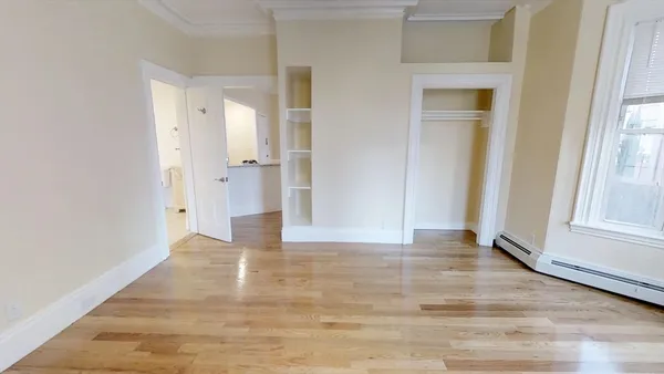 a view of an empty room with wooden floor and a window