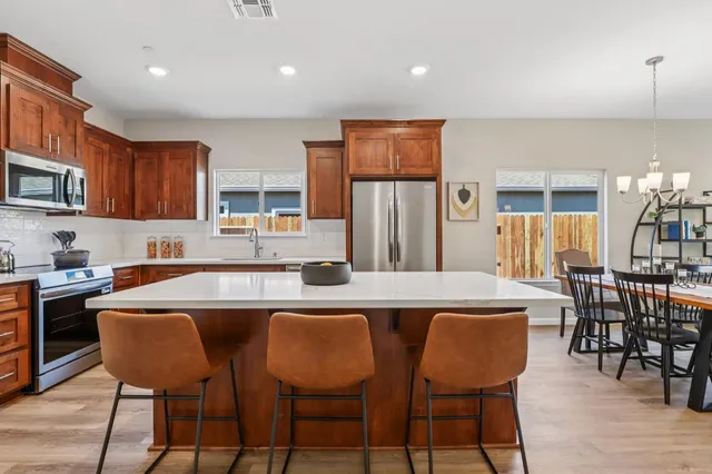 a kitchen with stainless steel appliances granite countertop a stove a sink a microwave a dining table and chairs
