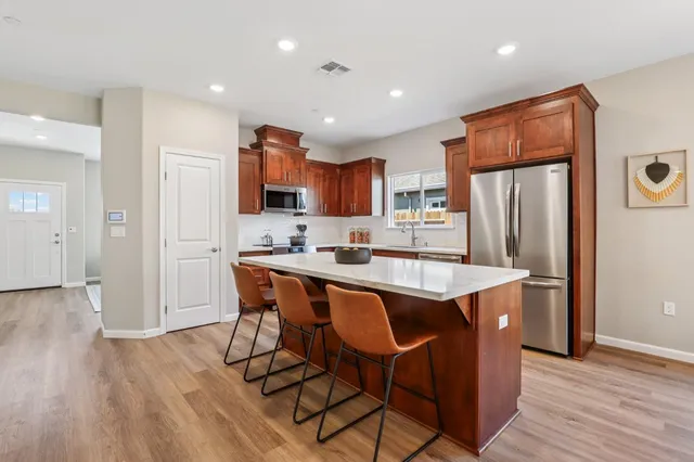 a kitchen with stainless steel appliances granite countertop a refrigerator a sink a stove a dining table and chairs