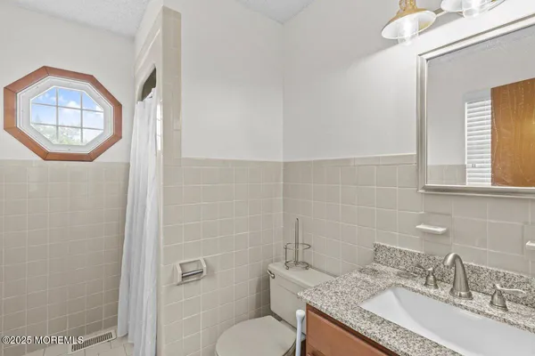 a bathroom with a granite countertop toilet a sink and mirror